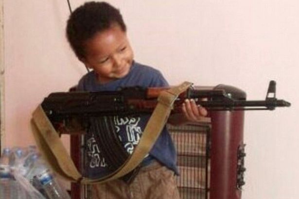 Victim: The little boy poses with an assault rifle 